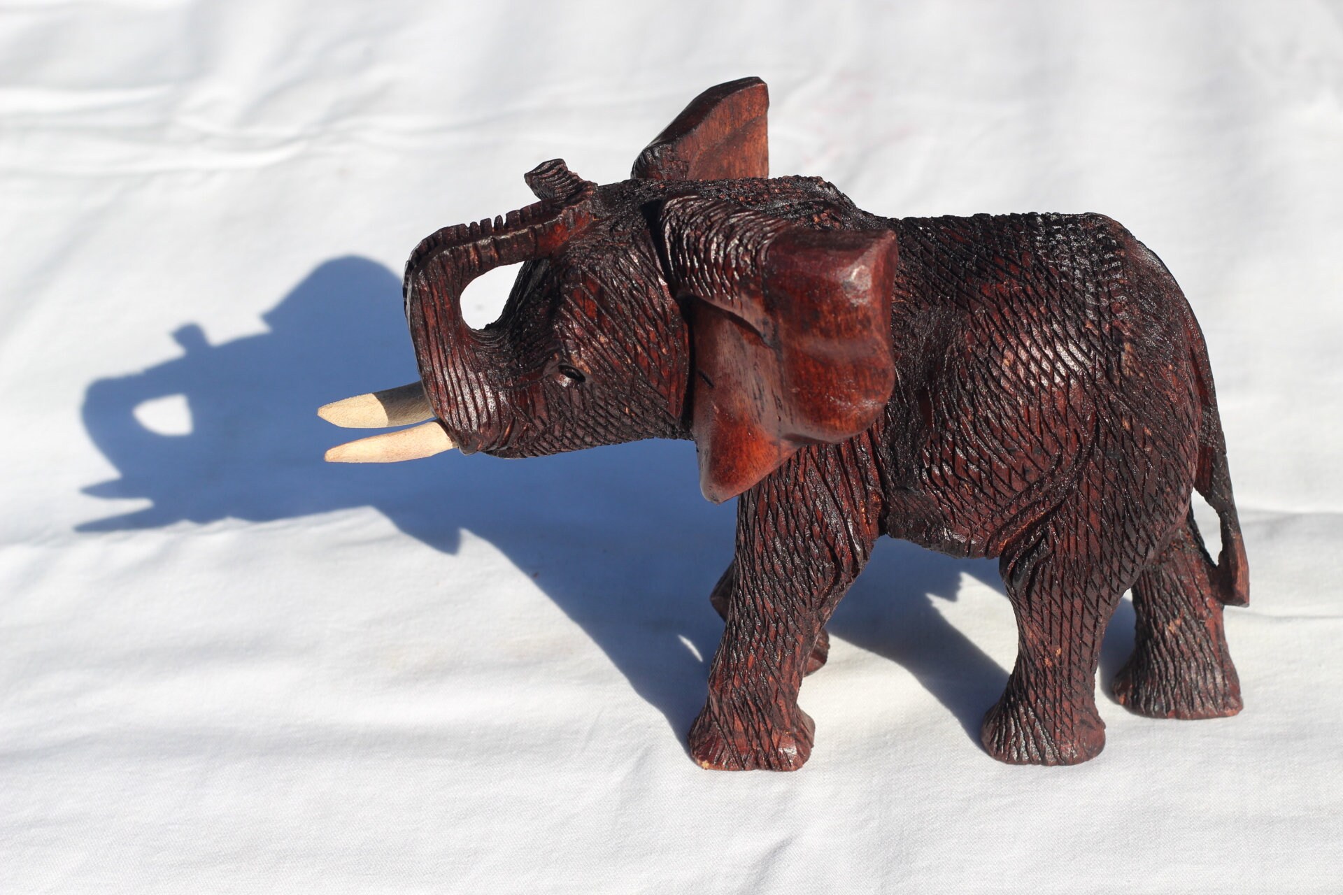 ジンバブエ産ムクワ材の手彫り象の鼻飾り（鼻の上）。ダークブラウンの