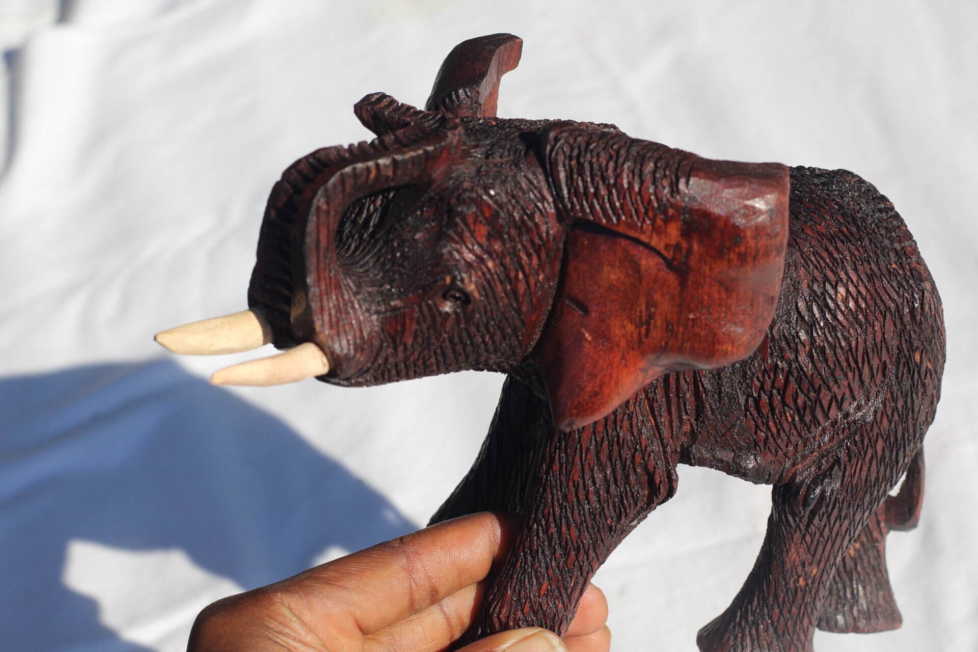 ジンバブエ産ムクワ材の手彫り象の鼻飾り（鼻の上）。ダークブラウンの