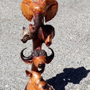 Puede incluir: Una escultura de madera de un elefante, un león, un búfalo y un rinoceronte apilados uno encima del otro. La escultura está hecha de madera marrón oscuro con detalles intrincados.
