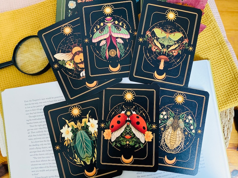 Peut inclure: Ensemble de dix cartes illustrant diff&eacute;rents insectes, chacun avec un symbole de lune et de soleil. Les cartes sont noires avec des accents dor&eacute;s et pr&eacute;sentent une vari&eacute;t&eacute; d'insectes, dont une coccinelle, un papillon de nuit et un scarab&eacute;e.