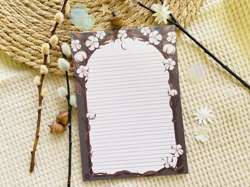 Pu&ograve; includere: Carta da lettere a righe con bordo floreale e di vite. Il design presenta fiori bianchi e batuffoli di cotone su sfondo marrone scuro. La carta &egrave; bianca con linee orizzontali per la scrittura. Elementi decorativi: ramoscelli e ghiande.