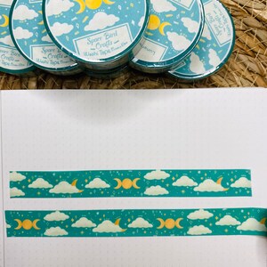 May include: A set of four teal and yellow washi tapes with a moon and stars design. The tapes are labeled "Space Bird Crafts" and "Lunar Eclipse".