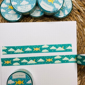 May include: A set of five teal blue washi tapes with a moon and cloud design. The tapes feature the text "Lunar Eclipse" and "Space Bird Crafts" with a gold crescent moon and stars.