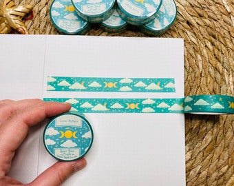 May include: A roll of teal washi tape with a moon and cloud design. The tape is labeled "Lunar Eclipse" and "Space Bird Crafts".