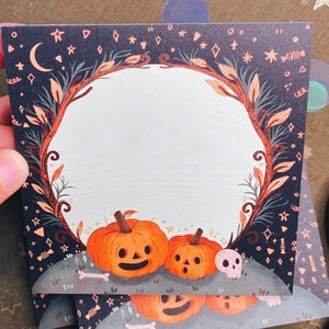 May include: Square Halloween-themed cards with a pumpkin illustration. The cards feature a dark blue background with stars, moons, and a decorative border. The pumpkins are orange with carved faces. A skull and bones are also present.