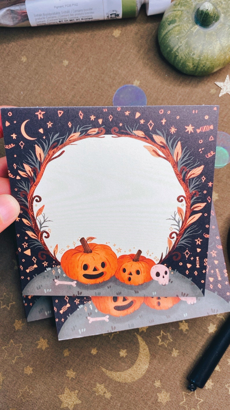 May include: Square Halloween-themed cards with a pumpkin illustration. The cards feature a dark blue background with stars, moons, and a decorative border. The pumpkins are orange with carved faces. A skull and bones are also present.