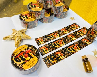 May include: A roll of black and gold washi tape with a repeating pattern of mushrooms, crescent moons, and stars. The tape is labelled "Mystic Mushroom Space Bird Crafts".