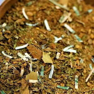 Può includere: Una ciotola di legno piena di un mix di erbe secche, foglie e carta tritata. Il mix è di colore marrone chiaro con accenti verdi e bianchi.