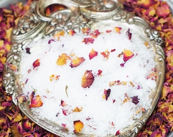 Peut inclure: Un plat en forme de cœur en argent rempli de sels de bain blancs et de pétales de rose. Le plat est entouré de plus de pétales de rose sur un plateau en argent avec le mot "LOVE" répété sur le bord.