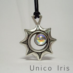 Puede incluir: Colgante plateado con diseño de sol, con un orbe iridiscente central. El colgante cuelga de un cordón negro. El texto "Unico Iris" está en la parte inferior.