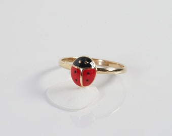 May include: A gold ring with a red and black ladybug design.