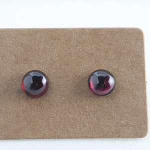 Peut inclure: Une paire de boucles d'oreilles clous avec des pierres rondes de couleur rouge foncé.