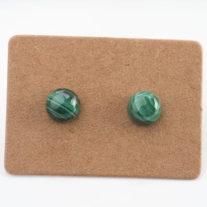 Peut inclure: Une paire de boucles d'oreilles en malachite verte sur une carte marron.