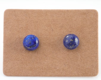 Könnte beinhalten: Ein Paar blaue Lapislazuli-Ohrstecker mit goldenen Flocken auf braunem Hintergrund.