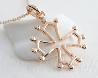 May include: A rose gold pendant necklace featuring a stylized cross design. The pendant has a four-pointed shape with rounded accents at each point. The necklace chain is also rose gold.