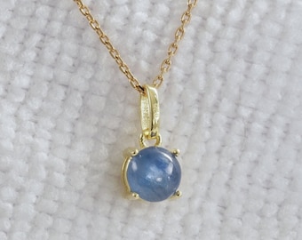 May include: A gold chain necklace with a pendant featuring a round, light blue gemstone.