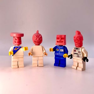 May include: Four small, red, plastic figurines with different facial expressions and designs. The figurines are standing on a white surface.