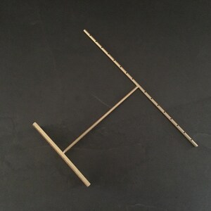 Pode incluir: Um suporte de joias de metal dourado com um design em forma de T. O suporte tem v&aacute;rios orif&iacute;cios para pendurar brincos ou colares.