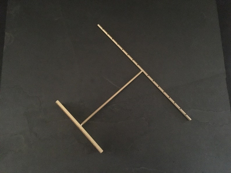 Pode incluir: Um suporte de joias de metal dourado com um design em forma de T. O suporte tem v&aacute;rios orif&iacute;cios para pendurar brincos ou colares.