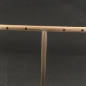 Peut inclure: Un pr&eacute;sentoir &agrave; bijoux en m&eacute;tal argent&eacute; avec une barre horizontale et un poteau vertical. La barre comporte quatre petits trous pour tenir les boucles d'oreilles.