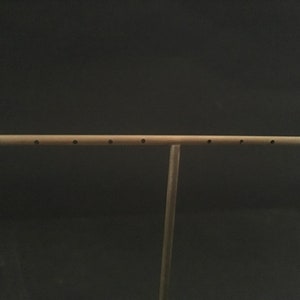 Pode incluir: Um suporte para brincos de metal dourado com uma barra horizontal e v&aacute;rios furos para pendurar brincos.