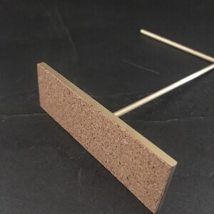 Peut inclure: Un support en m&eacute;tal dor&eacute; avec une base rectangulaire en li&egrave;ge. Le support est con&ccedil;u pour tenir un petit objet, comme un t&eacute;l&eacute;phone ou un livre.