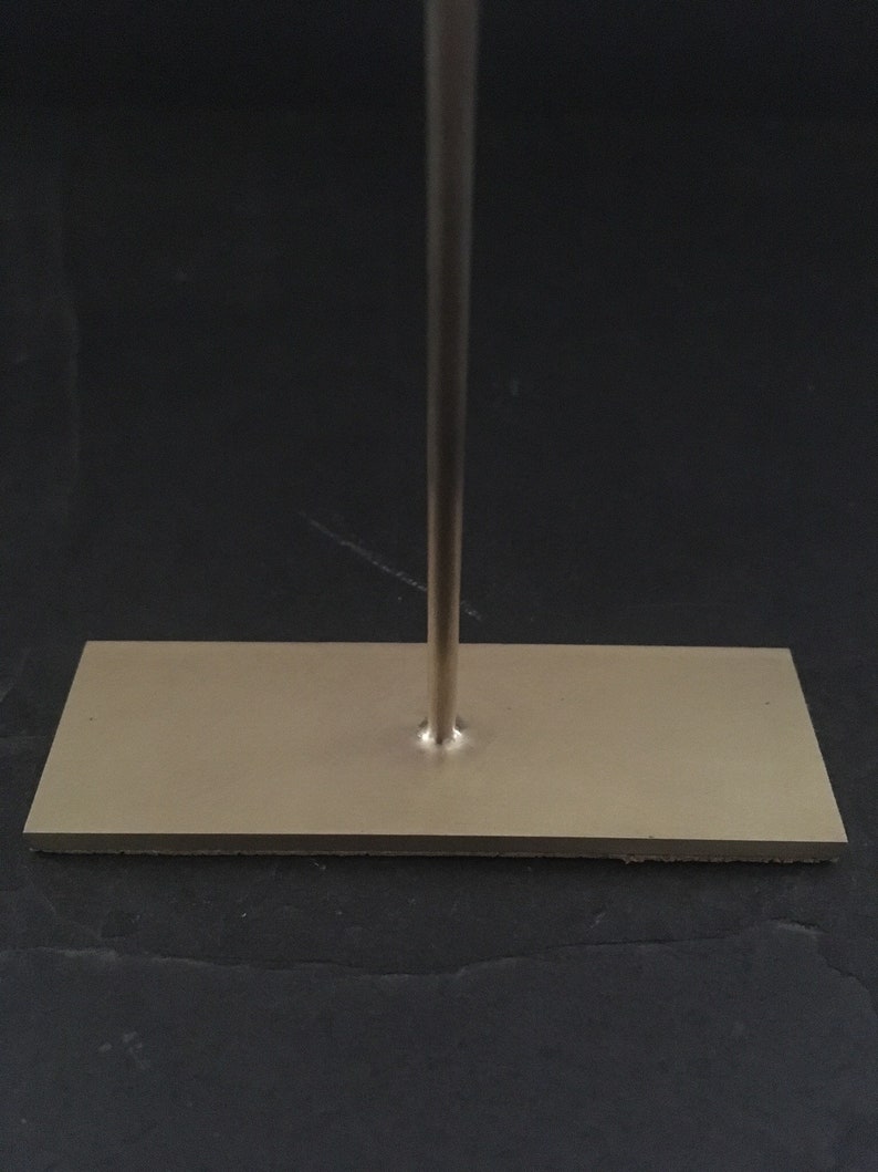 Peut inclure: Un support en m&eacute;tal argent&eacute; avec une base rectangulaire. Le support a une seule tige verticale qui s'&eacute;tend de la base.