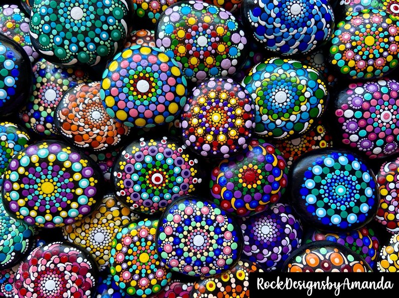 May include: A collection of colorful, hand-painted rocks with mandala designs. Each rock features a unique pattern of dots and swirls in various shades of blue, green, red, yellow, purple, and white.