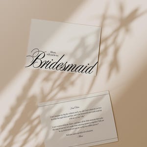 May include: Two white cards with black text. The top card reads "Allison, will you be my Bridesmaid" in elegant script. The bottom card contains a longer message with a decorative border. The cards are on a neutral background with shadows.