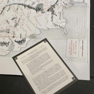 Pode incluir: Um mapa preto e branco da Terra-m&eacute;dia de O Senhor dos An&eacute;is, com um close-up de um trecho de texto do ep&iacute;logo do livro. O texto explica que o ep&iacute;logo foi escrito pelo filho de J.R.R. Tolkien, Christopher Tolkien, ap&oacute;s a morte de seu pai.