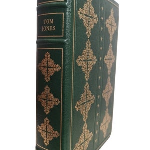 Puede incluir: Un libro encuadernado en cuero verde con letras doradas. El título es "Tom Jones" de Henry Fielding. El libro forma parte de la colección "The Franklin Library".