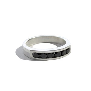 May include: A silver band ring with a row of black gemstones.