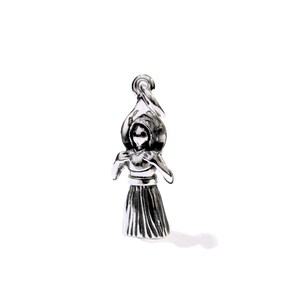 Puede incluir: Un amuleto de plata que representa a una mujer con un sombrero de ala ancha y un vestido largo.