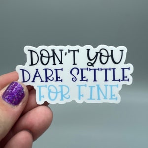 May include: White sticker with the text "Don't you dare settle for fine" in black, blue, and light blue lettering.