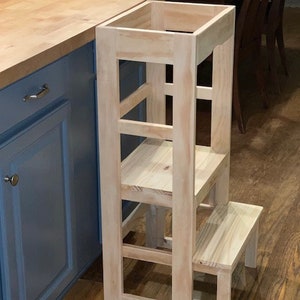 Puede incluir: Un taburete de madera con cuatro pelda&ntilde;os y una plataforma superior. El taburete est&aacute; hecho de madera sin tratar y tiene un color natural. Est&aacute; dise&ntilde;ado para ayudar a los ni&ntilde;os a alcanzar superficies m&aacute;s altas.