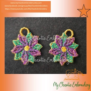 May include: Two purple, green, and gold embroidered flower charms with a loop at the top. The charms are on a black background.
