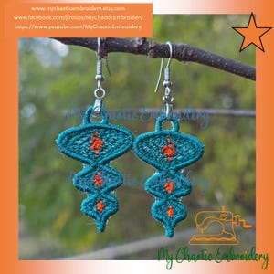 May include: Embroidered teal and orange dangle earrings. The earrings are made of teal fabric with an orange floral design. The earrings are hanging from a branch. The text "My Chaotic Embroidery" is visible.
