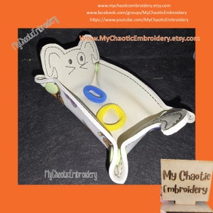 May include: A white felt bunny-shaped trinket tray with a blue and yellow hair tie inside. The tray has a stitched edge and is decorated with colorful embroidery. The text "My Chaotic Embroidery" is visible on the tray and in the bottom right corner of the image.