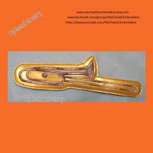 May include: Gold embroidered patch of a trombone, with the text "MyChaoticEmbroidery" on the bottom.