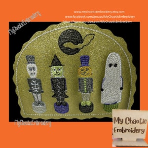 May include: A gold glitter background with a black bat and moon.  Four embroidered figures stand in front of the moon: a skeleton, a witch, a pumpkin, and a ghost.  The text "My Chaotic Embroidery" is at the bottom of the image.