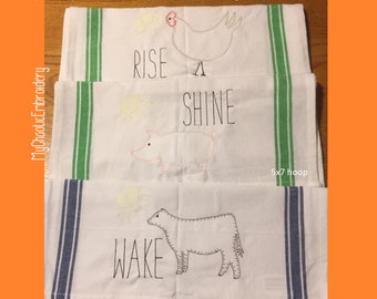 May include: Three white kitchen towels with embroidered designs. The top towel features a chicken and the text "Rise and Shine". The middle towel features a pig and the text "Shine". The bottom towel features a cow and the text "Wake". All towels have green and blue stripes on the sides. The towels are 5x7 hoop size.