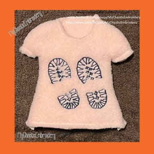 May include: A pink t-shirt with black embroidered boot prints. The shirt has short sleeves and a crew neck. The text "MyChaoticEmbroidery" is visible on the bottom of the shirt.