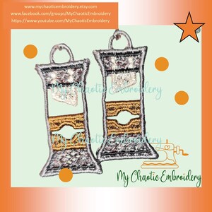 May include: Two silver and gold embroidered patches in the shape of a lighthouse. The patches are on a light green background with orange circles and a yellow star.
