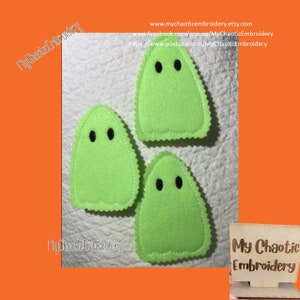 Puede incluir: Tres formas de fantasmas de fieltro verde con ojos bordados negros. Los fantasmas están sobre una superficie blanca. El texto "My Chaotic Embroidery" es visible en la esquina inferior derecha de la imagen.