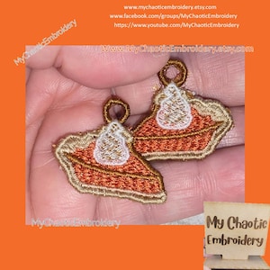 Può includere: Toppe ricamate a forma di fetta di torta, con dettagli arancioni, beige e bianchi. Ogni toppa ha un anello nella parte superiore per l'attacco. Il testo "My Chaotic Embroidery" e un indirizzo web sono visibili.