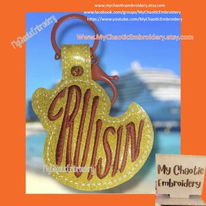 May include: A yellow glitter keychain with a red embroidered word "CRUISIN" and a small red rhinestone. The keychain is attached to a silver key ring.