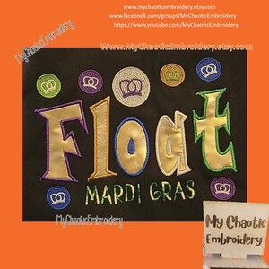 May include: Embroidered design on a black fabric background. The design features the word "Float" in gold and green lettering with a purple outline. Below the word "Float" is the text "Mardi Gras" in green lettering. The design is surrounded by small, colorful embroidered crowns.