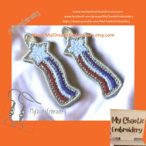 May include: A pair of silver earring hooks with a red, white, and blue star-shaped embroidered charm. The charms are shaped like a shooting star with a white star at the top. The charms are embroidered with a white, red, and blue design. The charms are attached to the earring hooks with a silver loop. The charms are on a white background. The text "My Chaotic Embroidery" is visible in the image.