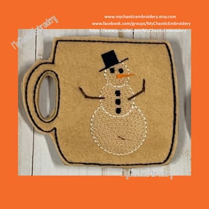 Può includere: Scaldamug in feltro ricamato con un disegno di pupazzo di neve. Il pupazzo di neve indossa un cappello a cilindro nero e ha un naso di carota. Lo scaldamug è marrone con cuciture nere.