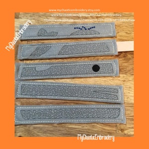 Puede incluir: Cinco tiras de fieltro gris con bordado negro de un diseño de ballena. Las tiras están dispuestas verticalmente sobre una superficie de madera. El texto "MyChaoticEmbroidery" aparece en la parte superior e inferior de la imagen.